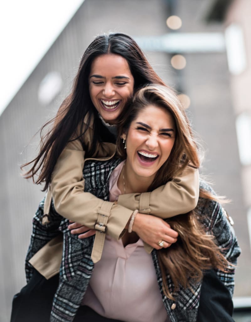 Two women laughing together, one playfully carrying the other on her back.