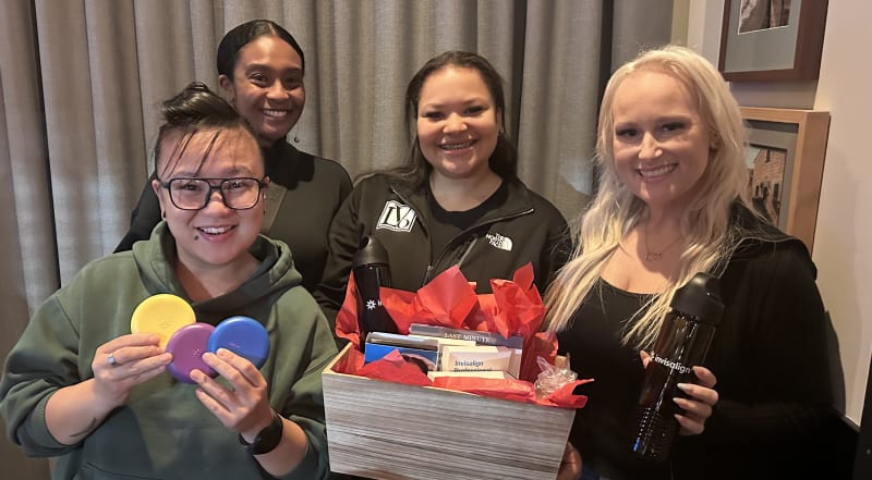 Staff members at Leone & Vaughn Orthodontics smiling and posing with gift items 