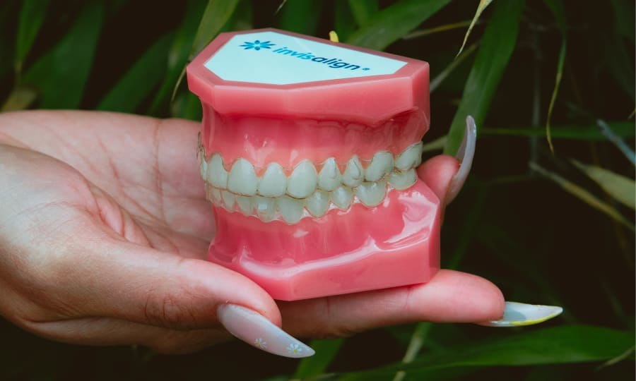 A woman with white teeth slides on a set of Invisalign clear aligners.