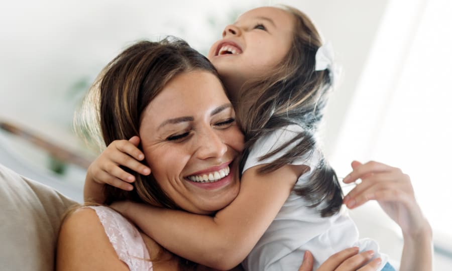 A woman and child are hugging and laughing.