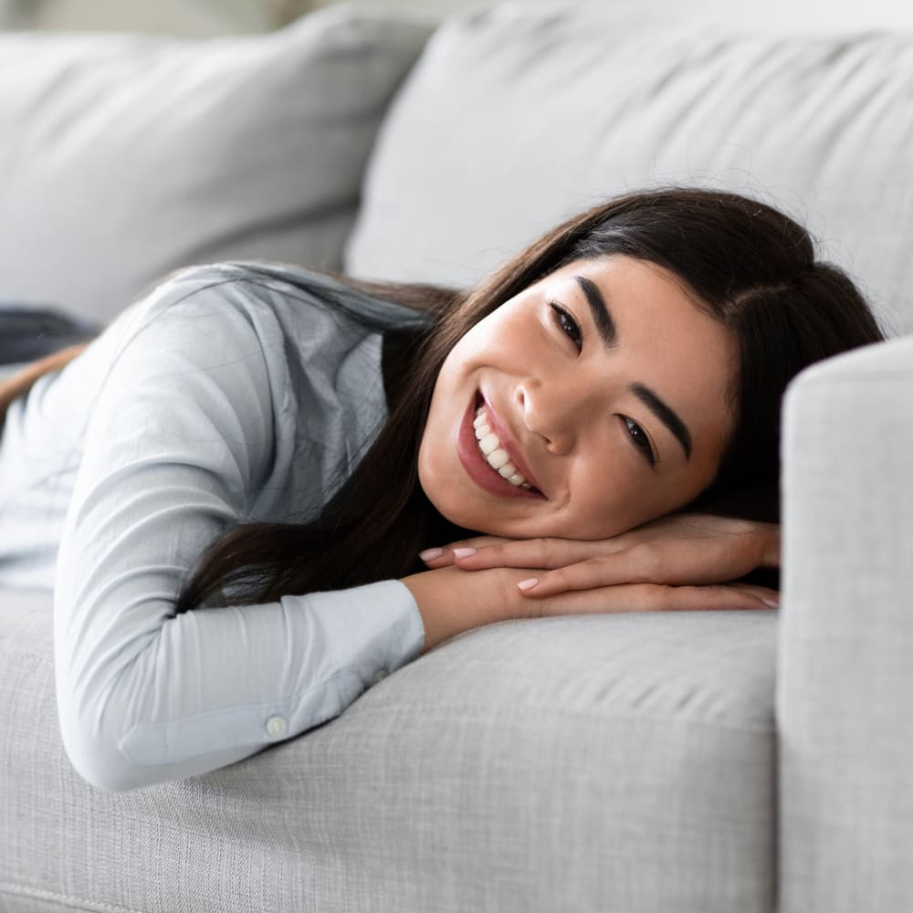 A man is sitting on his bed smiling, seemingly just woken up from a good night's sleep.