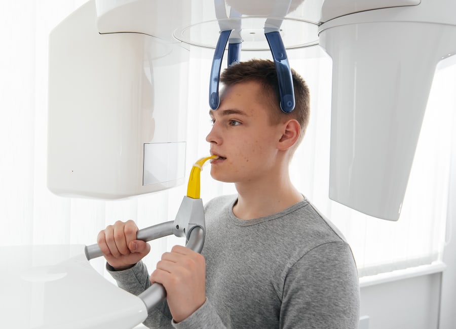 A patient sits with their face in a 3D iCAT Scan machine.